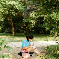 A student writes among the trees of Grand Valley's campus.